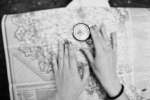 Close-up photo of female hands with compass on a map.