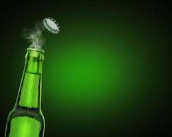 cold wet open beer bottle with smoke on green background photo