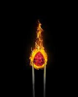 Shiny brilliant diamond red placed on fire on black background in diamond tweezers. 3d render photo