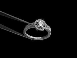 Diamond ring. in tweezers on a black background photo