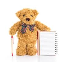 oso de peluche con bolígrafo y cuaderno en blanco foto