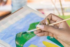 Hand with brush and paint by watercolors photo