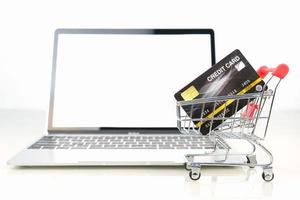 Credit card in shopping cart front of laptop blank screen photo