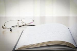 Book and eyeglasses with on the desk photo