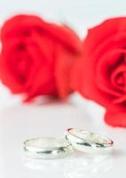 rosa roja y anillo de bodas en blanco foto