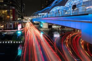 paisaje urbano de bangkok por la noche con iluminación de skywalk y vehículos foto