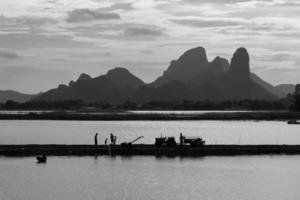 Landscpae of Mountain and Lake with Silhouette of People Working in Field in Lopuri Thailand photo