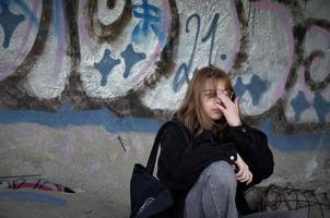 St. Petersburg, Russia, 06.01.2022. A teenage girl sits in an abandoned building painted with graffiti and smokes photo