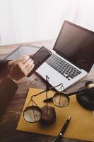 Justice and law concept.Male judge in a courtroom with the gavel, working with, computer and docking keyboard, eyeglasses, on table in morning light photo