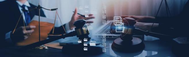 Justice and law concept.Male judge in a courtroom with the gavel, working with, computer and docking keyboard, eyeglasses, on table in morning light photo