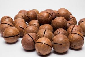 Whole macadamia nuts on the white background. Healthy vegetarian snack. Close-up photo. Copy-space for your text. High quality photo