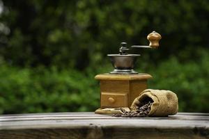 Vintage coffee grinder.Old retro hand-operated wooden and metal coffee grinder.Manual coffee grinder for grinding coffee beans. on the old wooden background. photo