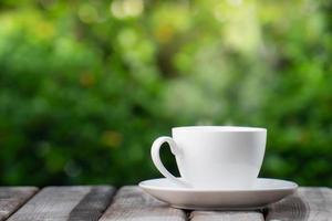 concepto de bebida de café caliente, taza de café blanco de cerámica caliente con humo en una mesa de madera antigua en un fondo natural. foto