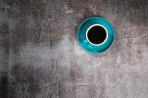 café negro en una taza de cerámica azul en el viejo piso de cemento gris foto