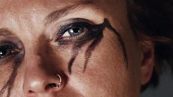 Melancholic woman with black eye make-up looking video