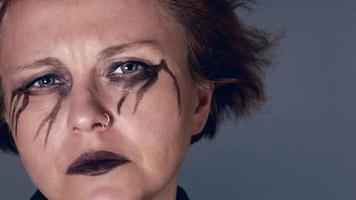 Melancholic woman with black eye make-up looking video