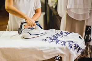 Caucasian housewife ironing on ironing board after laundry. photo