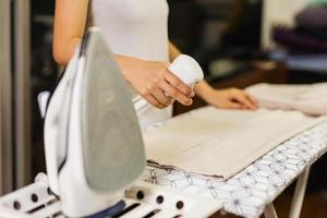 Housewife spray foggy for iron clothes on ironing board. photo