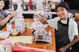 Young boy and his mum preparing ingredient for baking cake in kitchen. photo