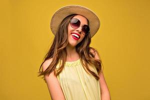 Stunning brunette female model posing with smile on yellow background. Close-up portrait of stylish european girl standing in front of wall. photo