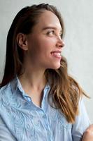 Happy exited girl with brown hair and pink lips is looking up with wonderful smile near the window in sun day. Pretty adorable lady resting at home photo