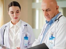 Selective focus at female doctor concentrate on consulting, discussing with male colleague in hospital. Two professional healthcare specialist standing in clinic brainstorming as medical teamwork. photo