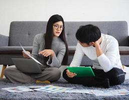 pareja de personas de negocios, mujer y hombre sentados juntos en casa usando una computadora portátil para una reunión en línea con el trabajo en equipo de inicio. joven empresaria asiática trabajando, planificando o discutiendo con un colega. foto