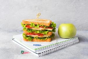 Healthy lunch for school with sandwich, fresh apple. Assorted colorful school supplies. Copy space. photo