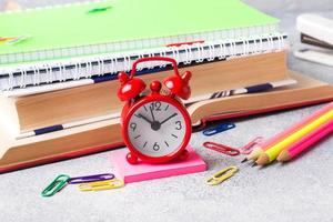 School supplies, clock book notebooks pencils on grey background with copy space. photo