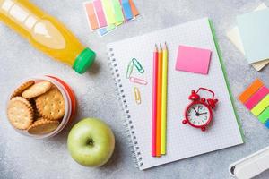 School supplies and Breakfast crackers, orange juice and fresh Apple on the grey table with copy space. concept school. photo