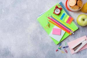 School supplies and Breakfast crackers, orange juice and fresh Apple on the grey table with copy space. concept school. photo