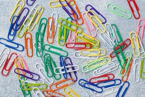 Bright colored paper clips on a gray Desk. concept school. close up photo