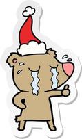 sticker cartoon of a crying bear wearing santa hat vector