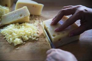 mujer preparando queso para cocinar usando rallador de queso en la cocina - gente haciendo comida con concepto de queso foto