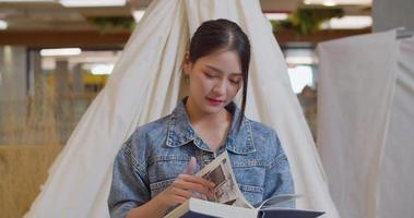 uma linda mulher asiática está feliz em ler um livro. câmera lenta 4k dci a filmagem enviada é um arranjo de filmagem de agrupamento video