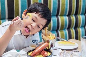 Asian boy eating French fries happily - child with unhealthy junk food concept