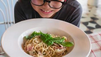 Boy happy eating spaghetti carbonara recipe - people enjoy with famous Italian dish food concept photo