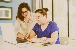 Vintage style photo of two business women are working with computer in modern office