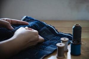 mujer vintage cosiendo tela a mano con bordados sobre fondo de mesa de madera - gente y concepto de tareas domésticas hechas a mano foto