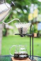 Man making drip fresh coffee in vintage coffee shop with green nature background - people with fresh coffee in nature concept photo