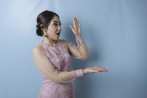 mujer sorprendida con ropa moderna de kebaya señalando el espacio de copia a su lado foto