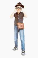 7 years old Asian traveler boy is standing and using binoculars in vintage color style photo