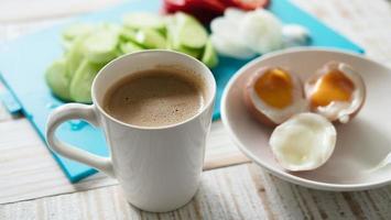 huevos cocidos con ensalada de pepino fresco y juego de desayuno con taza de café - vista superior concepto de comida para el desayuno foto