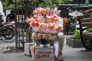 yogyakarta, indonesia - mayo de 2022 un hombre vende gulali hecho de masa de azúcar gruesa y caliente que se puede moldear en animales, flores y más. dulces tradicionales indonesios, gulali. foto