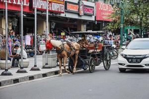 yogyakarta, indonesia - mayo de 2022 delman se detiene en jalan malioboro. delman es un transporte tradicional sobre ruedas que utiliza caballos como remolque. foto