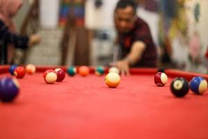 imagen borrosa del hombre preparándose para disparar apuntando la bola al objetivo en la piscina de billar roja foto