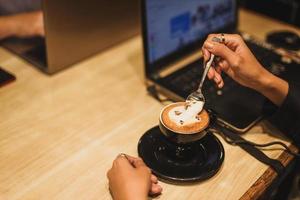 Woman's hand with latte art coffee in shape of cute cat with copy space. photo