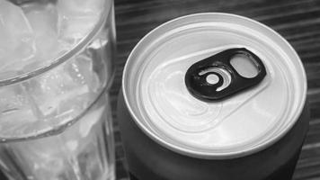 cerrado de lata de refresco rojo de aluminio con un vaso de cubitos de hielo. tono blanco y negro foto