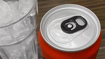 cerrado de lata de refresco rojo de aluminio con un vaso de cubitos de hielo. foto