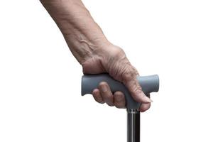 Closeup of senior hand holding a walking stick or a cane, isolated on white background. Medical and healthcare concept. photo